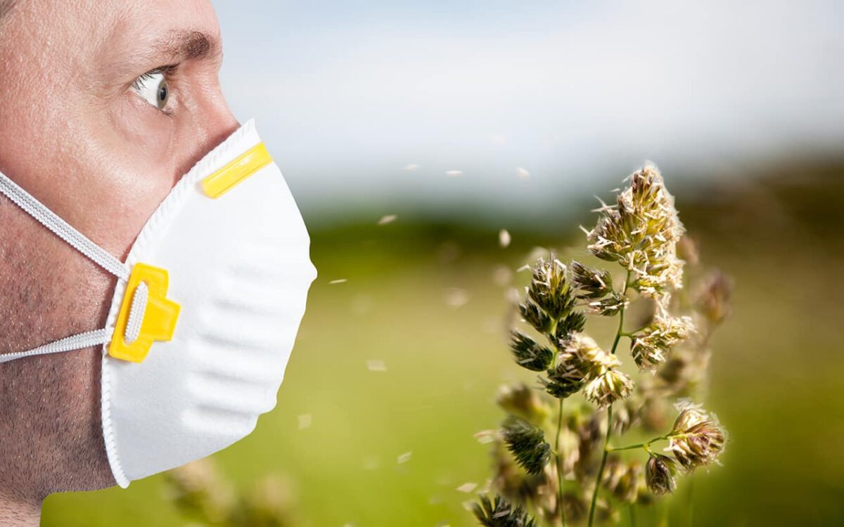 Mann mit Schutzmaske schützt sich vor Pollenallergie im Freien.