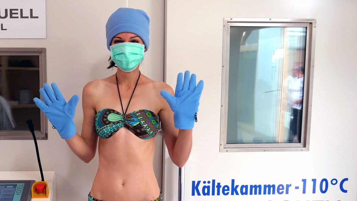 Frau in Bademode und Schutzkleidung in Kältekammer bei -110°C.