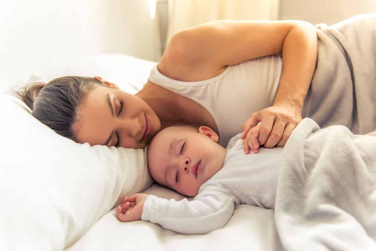 Mutter mit Baby schlafend im Bett, Frieden und Geborgenheit.
