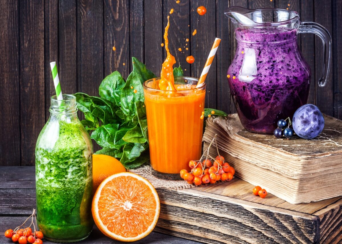 Drei bunte Smoothies: Grün, Orange, Lila mit frischen Früchten und Gemüse.