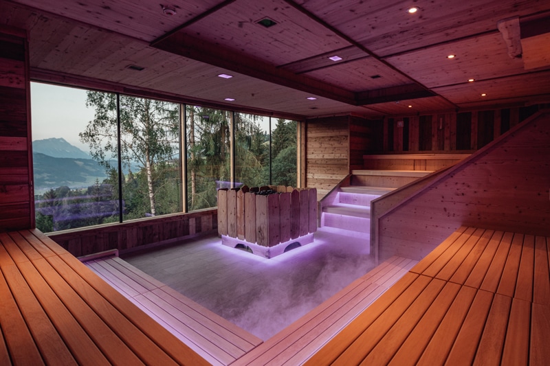Eine beleuchtete Wellness Sauna im Naturhotel Höflehner mit Blick auf die Berge